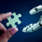 Human hand handing a robot hand a puzzle piece